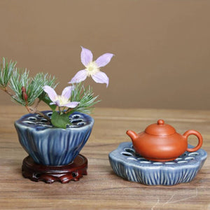 Vase Ikebana lotus bleu foncé avec arrangement de fleurs et théière en argile sur table en bois