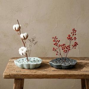 Deux vases Ikebana plats céladon et bleu gris avec arrangements floraux sur banc en bois vintage