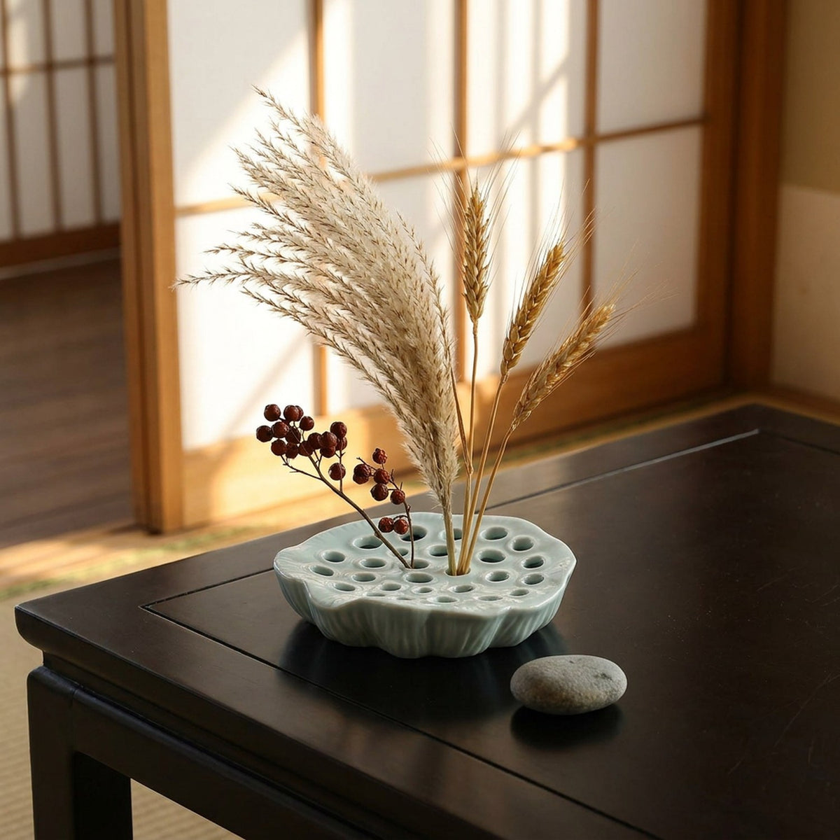 Vase Ikebana plat céladon avec composition florale zen sur table basse japonaise devant shoji