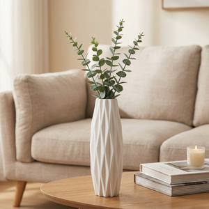 Vase blanc origami sur une table basse de salon avec des branches d eucalyptus