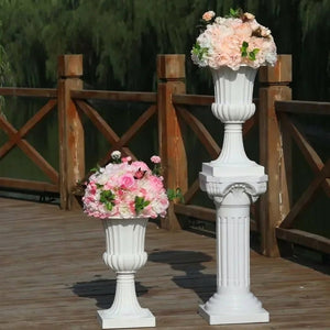 Vase médicis blanc dans un jardin fleuri avec des fleurs colorées en arrière-plan