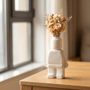 Vase robot céramique blanc avec bouquet de fleurs séchées sur bureau en chêne