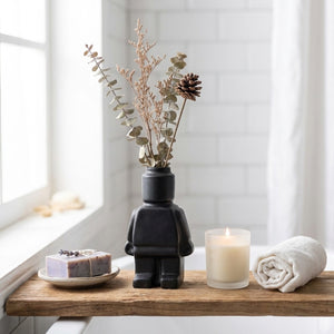 Vase robot avec fleurs séchées sur étagère de salle de bain