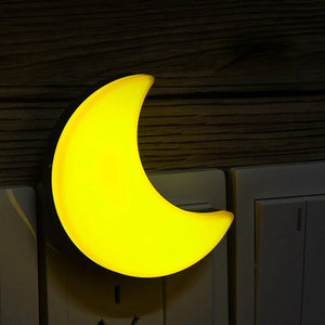 Veilleuse lune allumée en lumière chaude jaune branchée sur une prise murale
