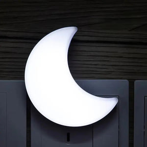 Veilleuse lune allumée en lumière blanche vue de près sur un mur sombre