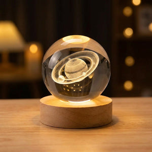 Lampe boule de cristal motif Saturne 3D allumée sur socle en bois