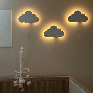 Trois veilleuses murales nuage allumées sur un mur avec halo lumineux chaud