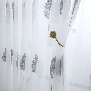 Voilage en tulle blanc retenu par une embrasse fleur dorée