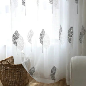 Voilage en tulle blanc au motif d'arbres brodé près d'un panier en osier