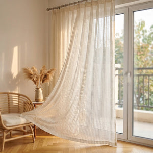 Voilage beige à rayures flottant près d'une porte de balcon vitrée