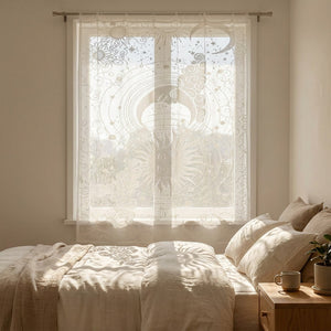 Voilage céleste blanc suspendu devant une fenêtre de chambre laissant filtrer une lumière douce sur le lit