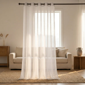 Voilage blanc transparent suspendu à une tringle devant une fenêtre lumineuse