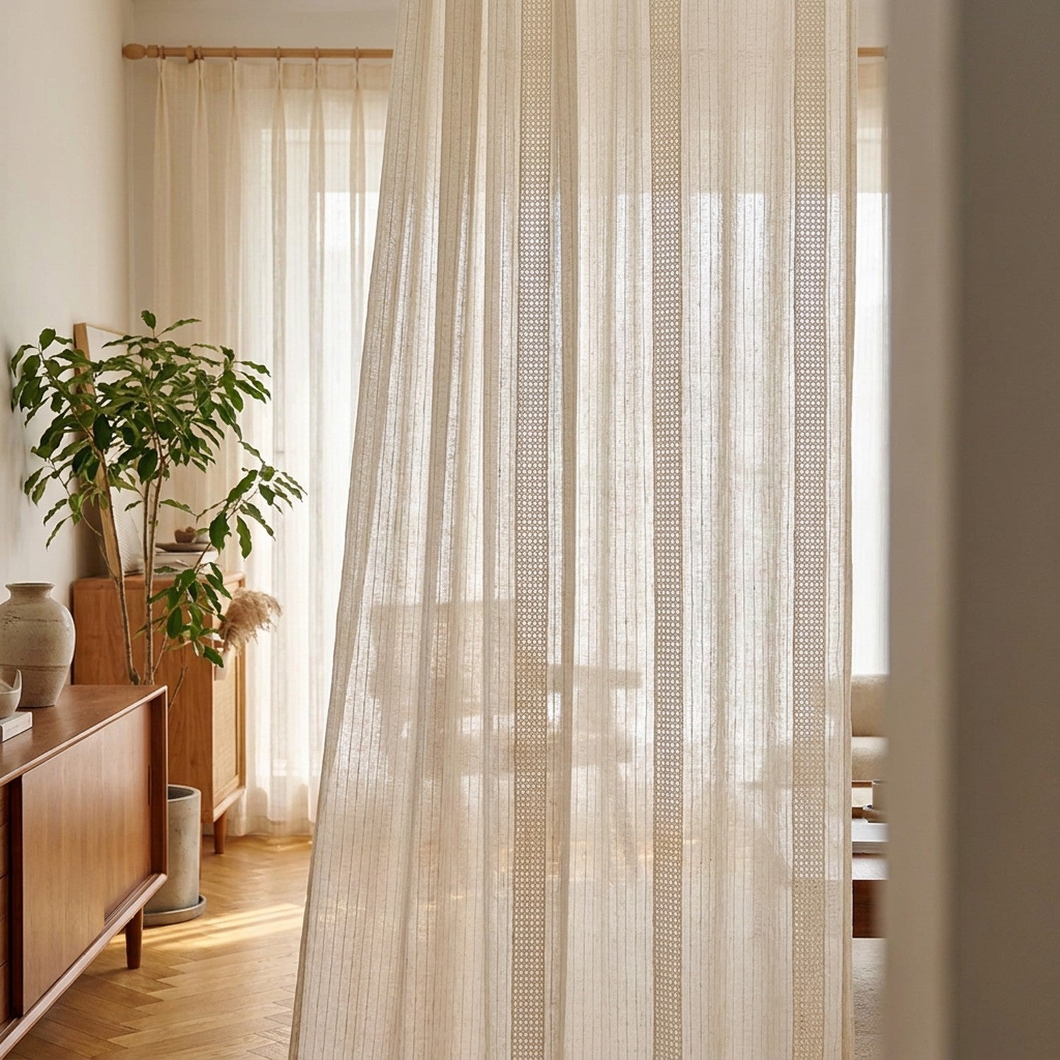 Voilage beige à rayures suspendu à une fenêtre de salon japandi ensoleillé