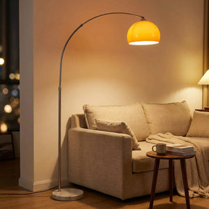 Lampadaire arc avec dôme en verre orange ambré allumé dans un salon