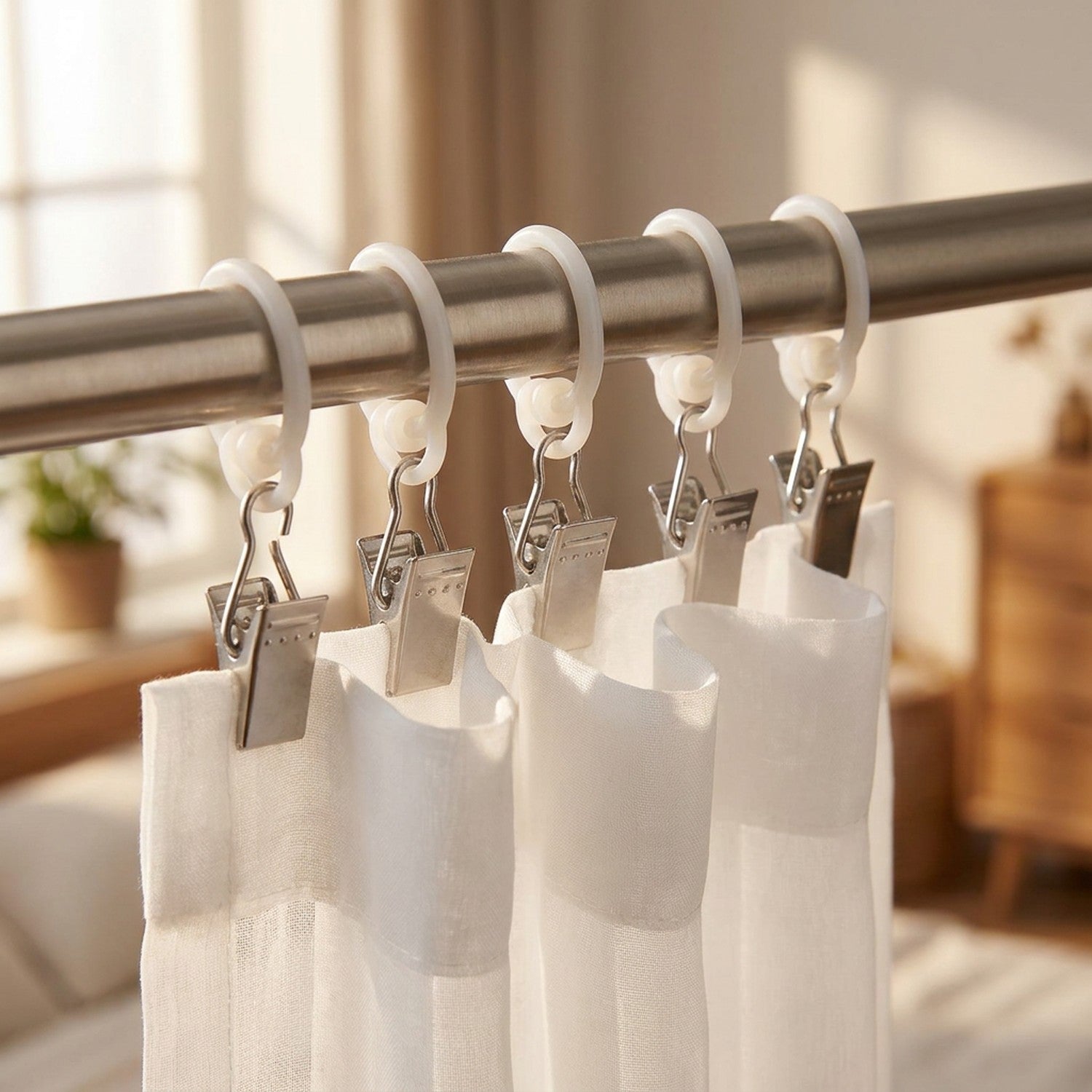 Pinces à rideau en métal argenté avec roulettes en nylon accrochées à une tringle tenant un rideau voilage blanc