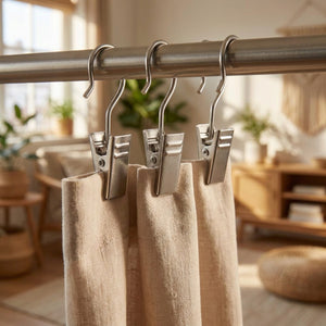 Pinces à rideau en acier inoxydable au crochet argenté accrochées à une tringle tenant un rideau beige