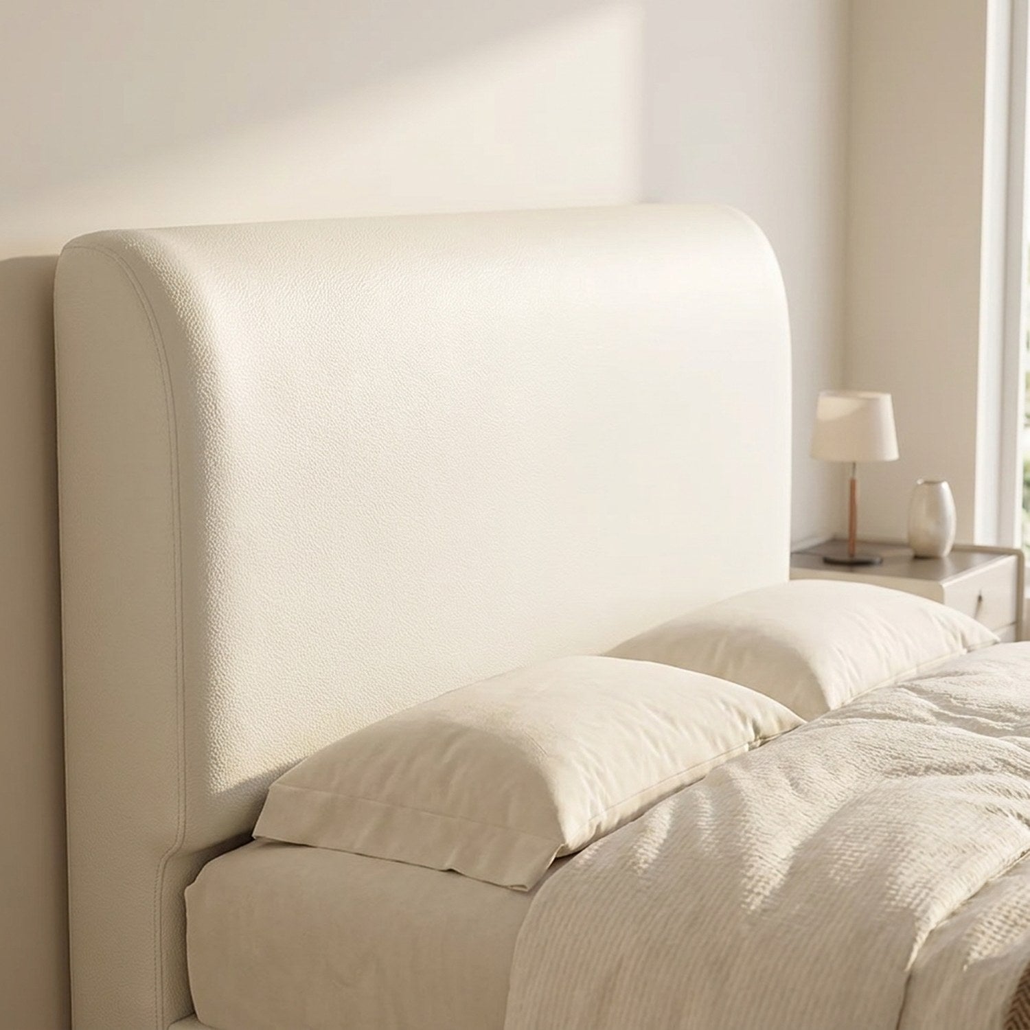 Housse de tête de lit effet cuir blanc installée sur un lit dans une chambre lumineuse