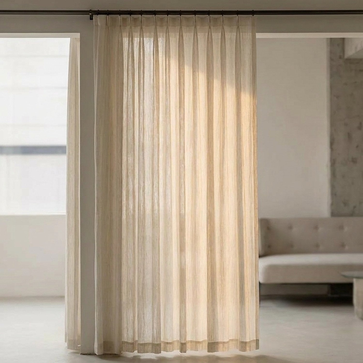 Voilage texturé beige suspendu à une grande fenêtre dans un salon lumineux