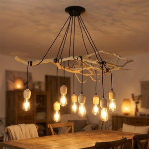 Lustre araignée façon bois flotté aux douilles en bois et ampoules Edison allumées au-dessus d'une table à manger
