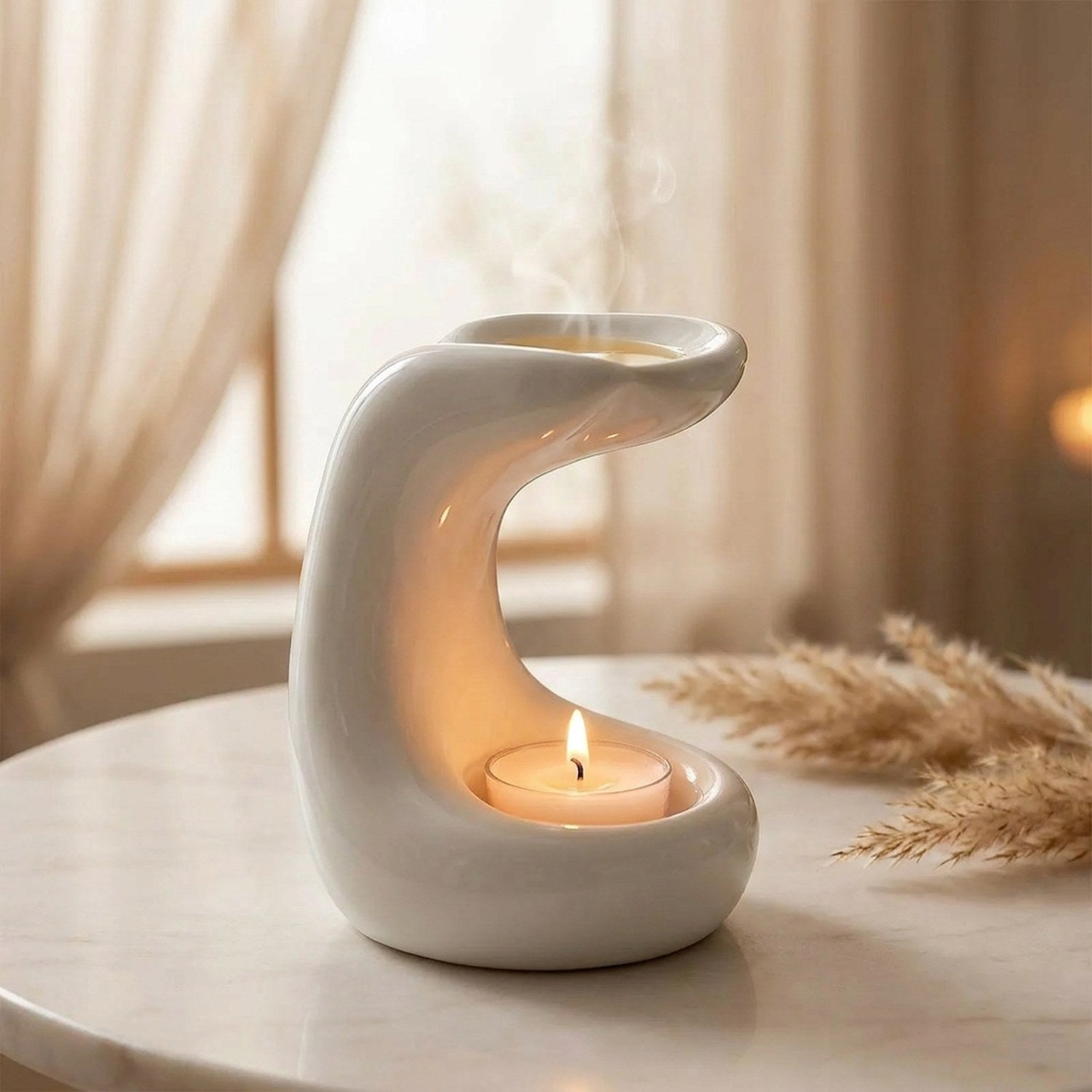 Brûle-parfum en céramique blanche à la courbe fluide avec une bougie chauffe-plat allumée sur une table en marbre