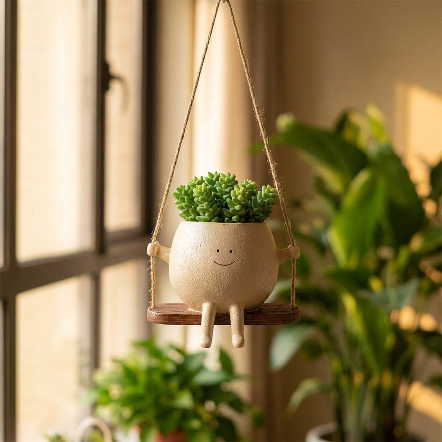 Pot de fleurs suspendu au visage souriant en résine crème avec une plante verte près d'une fenêtre