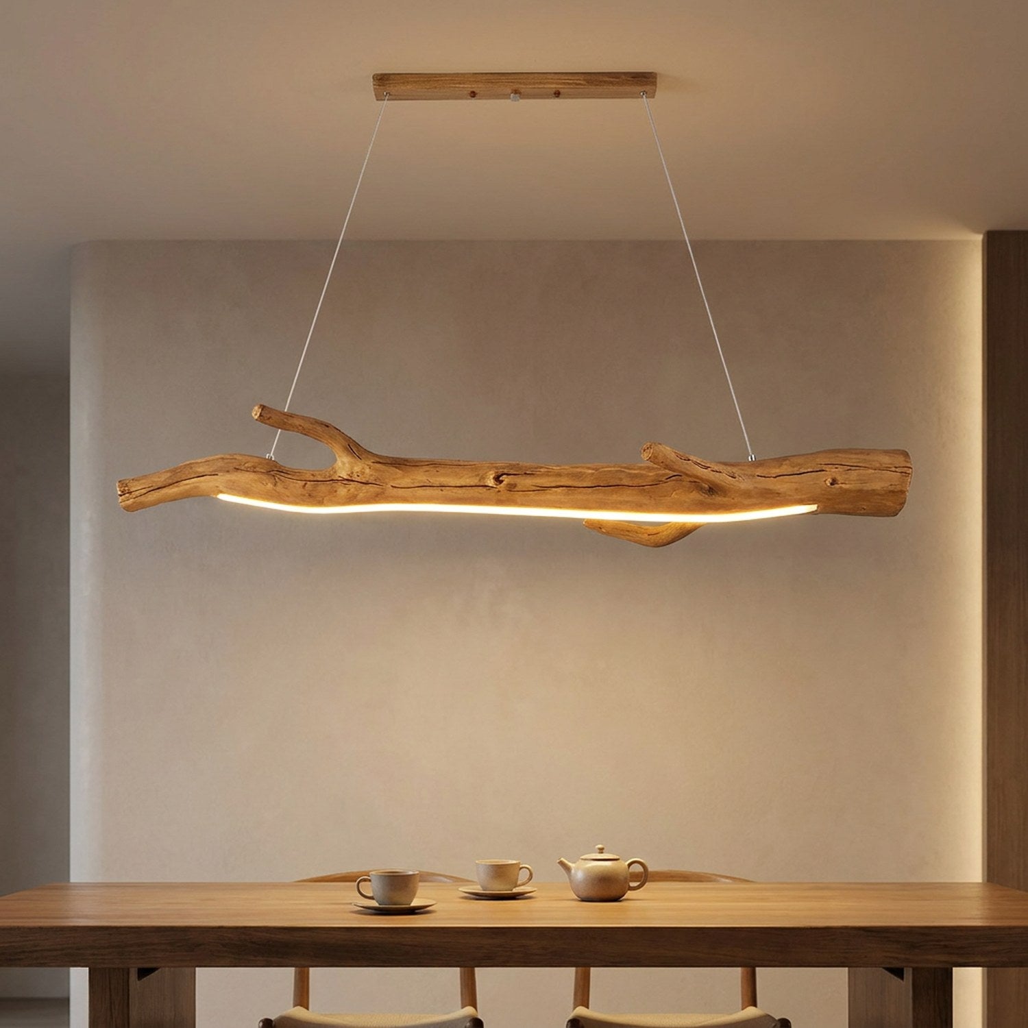 Lustre suspendu en résine noire imitant une branche allumé au dessus d'une table à manger dans un intérieur chaleureux