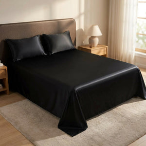 Drap housse en satin noir brillant sur un lit avec taies assorties dans une chambre chaleureuse