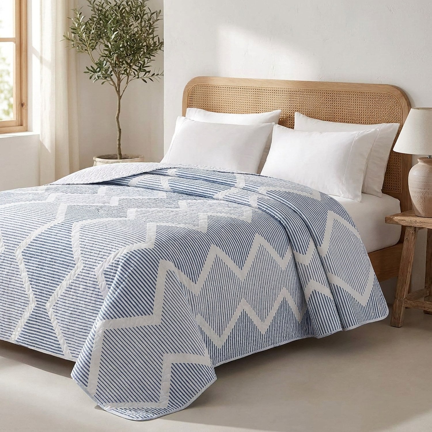 Jeté de lit réversible à chevrons bleus posé sur un lit dans une chambre méditerranéenne lumineuse