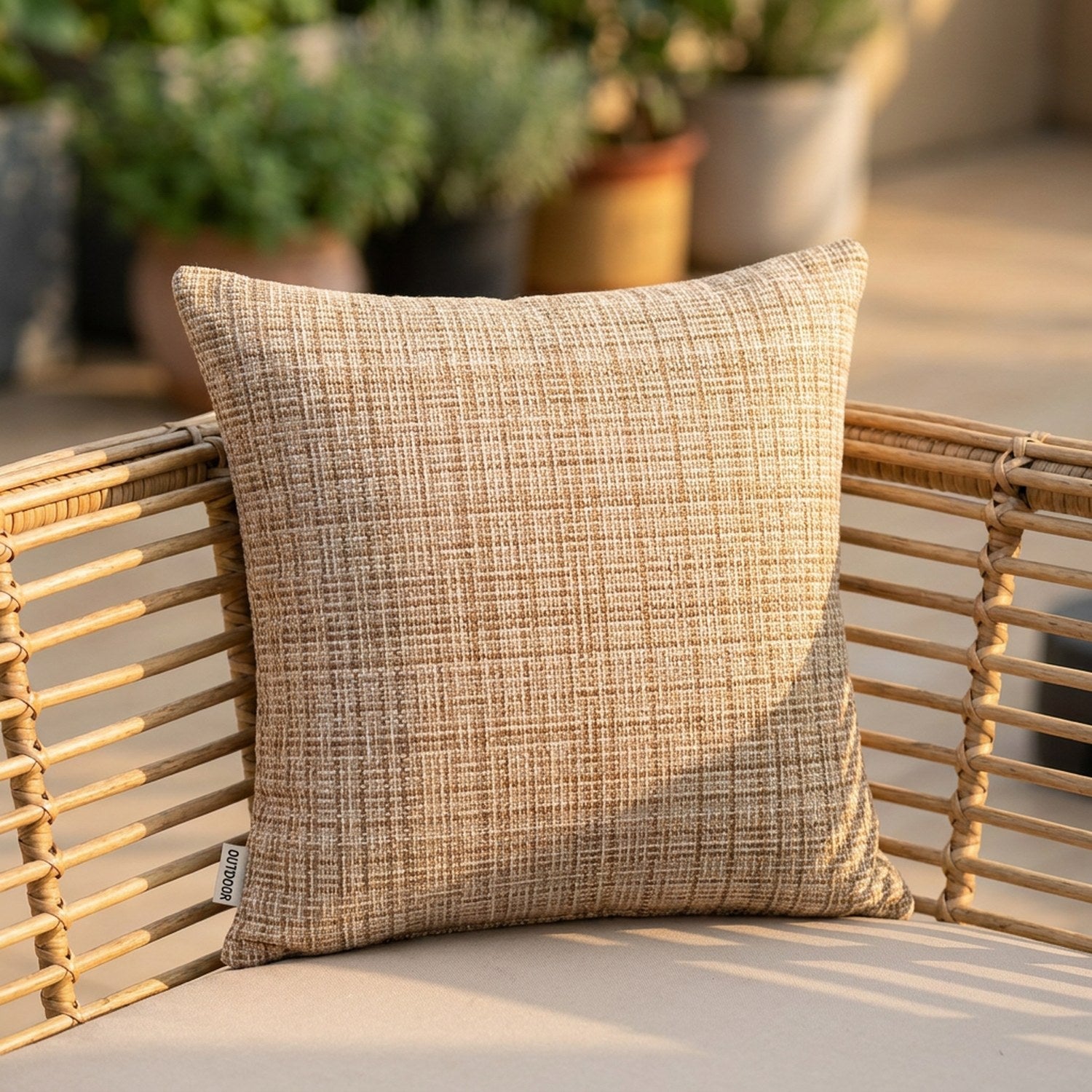 Housse de coussin d'extérieur imperméable beige au tissage texturé posée sur un canapé en rotin de terrasse