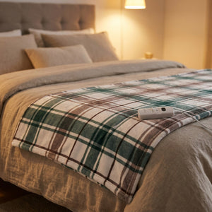 Couverture chauffante à carreaux verts drapée sur un lit avec sa commande thermostatée