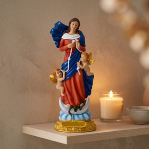 Statue de Marie qui défait les nœuds sur une étagère claire près d une bougie allumée