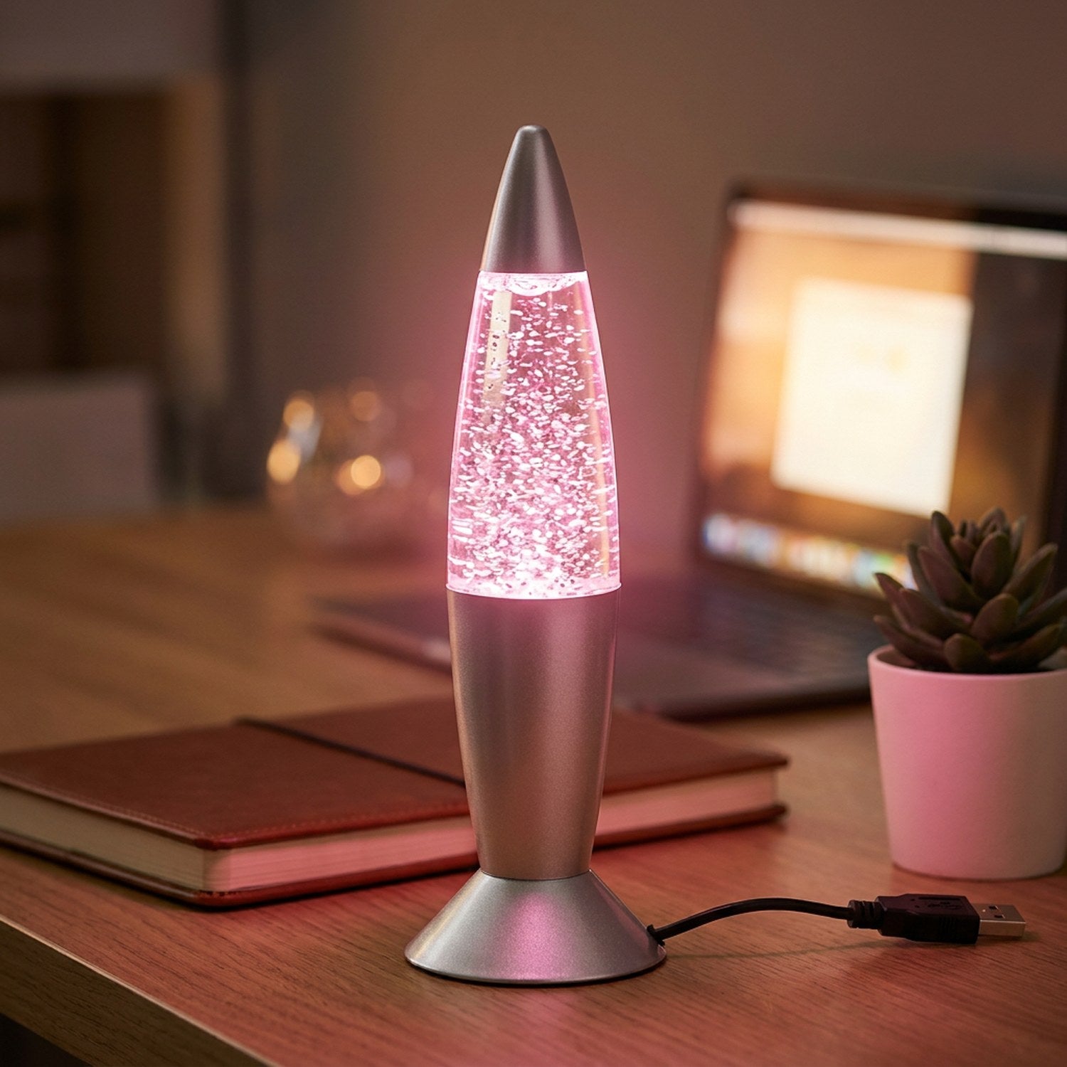 Lampe à lave USB argentée allumée en rose sur un bureau avec une plante succulente
