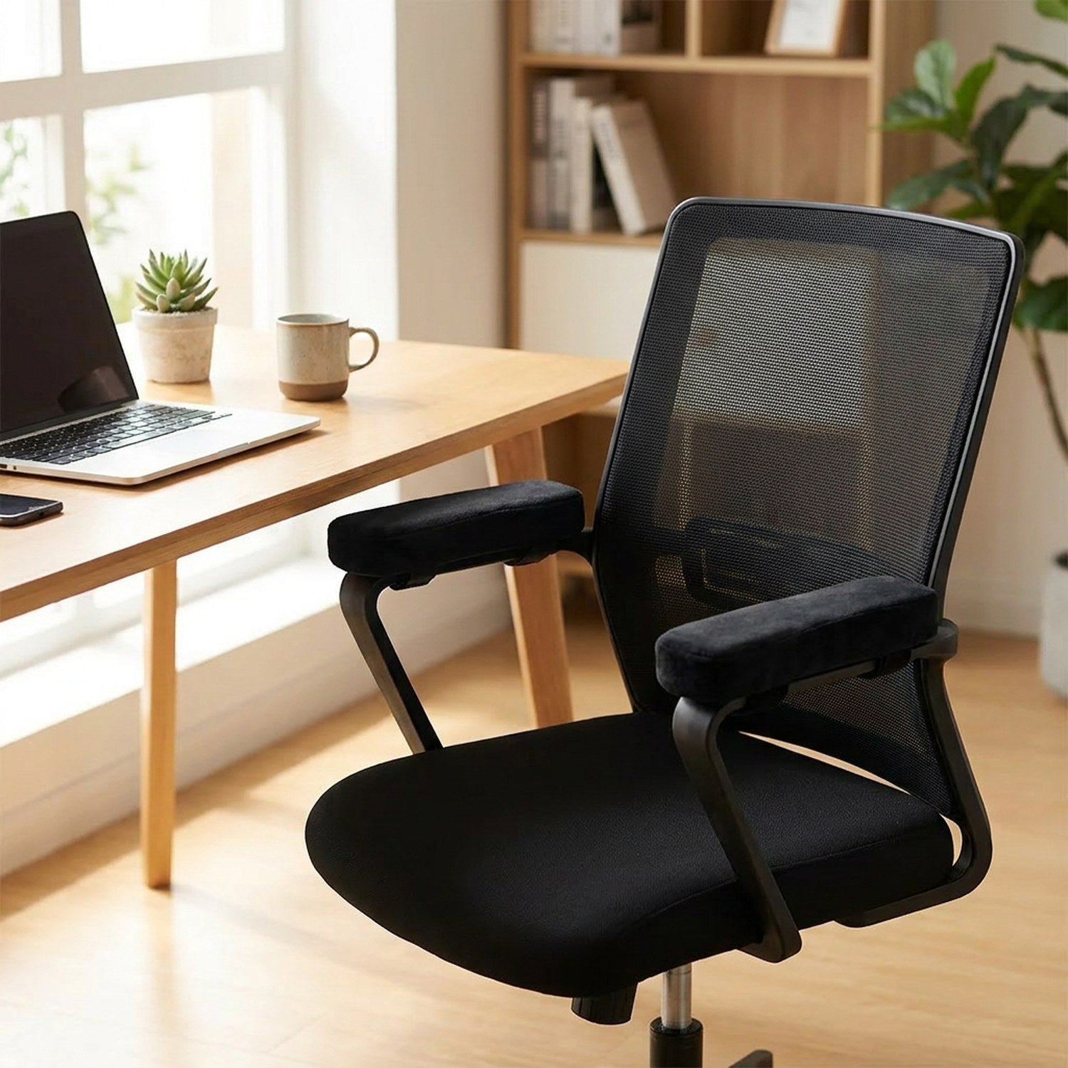 Chaise de bureau équipée de coussins d'accoudoir noirs dans un bureau lumineux avec ordinateur portable