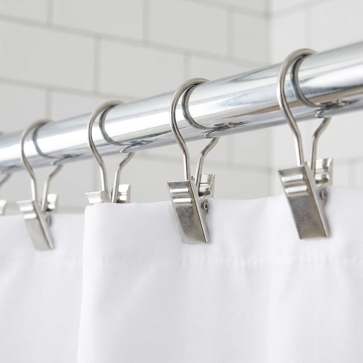 Rideau de douche blanc fixé à une tringle chromée grâce à des pinces à crochet