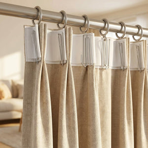 Rideau beige à plis pincés suspendu à une tringle avec des crochets à plis en métal