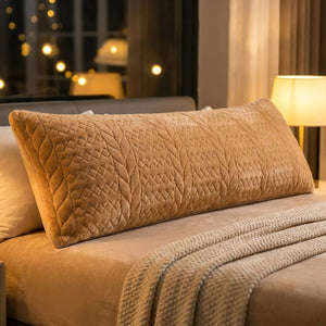 Housse de traversin peluche couleur caramel sur un lit avec lampe de chevet allumée le soir