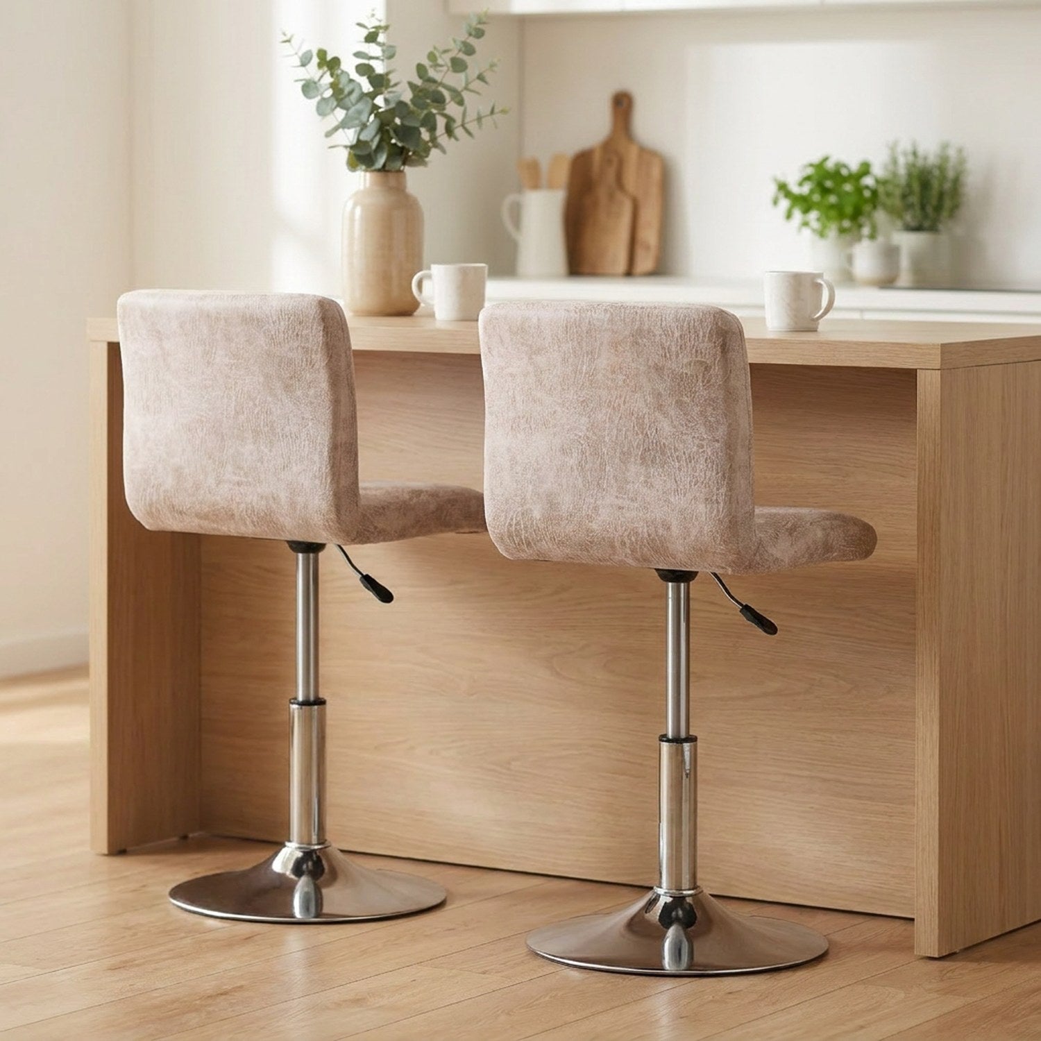 Deux housses de chaise de bar beige assorties sous un îlot de cuisine en bois clair