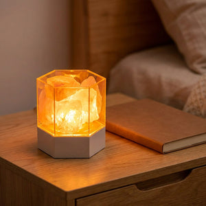 Lampe de sel hexagonale allumée sur une table de chevet avec un carnet