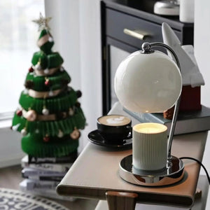 Lampe chauffe-bougie blanche près d'un café et d'un sapin de Noël miniature