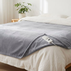 Couverture chauffante grise étalée sur un lit dans une chambre lumineuse