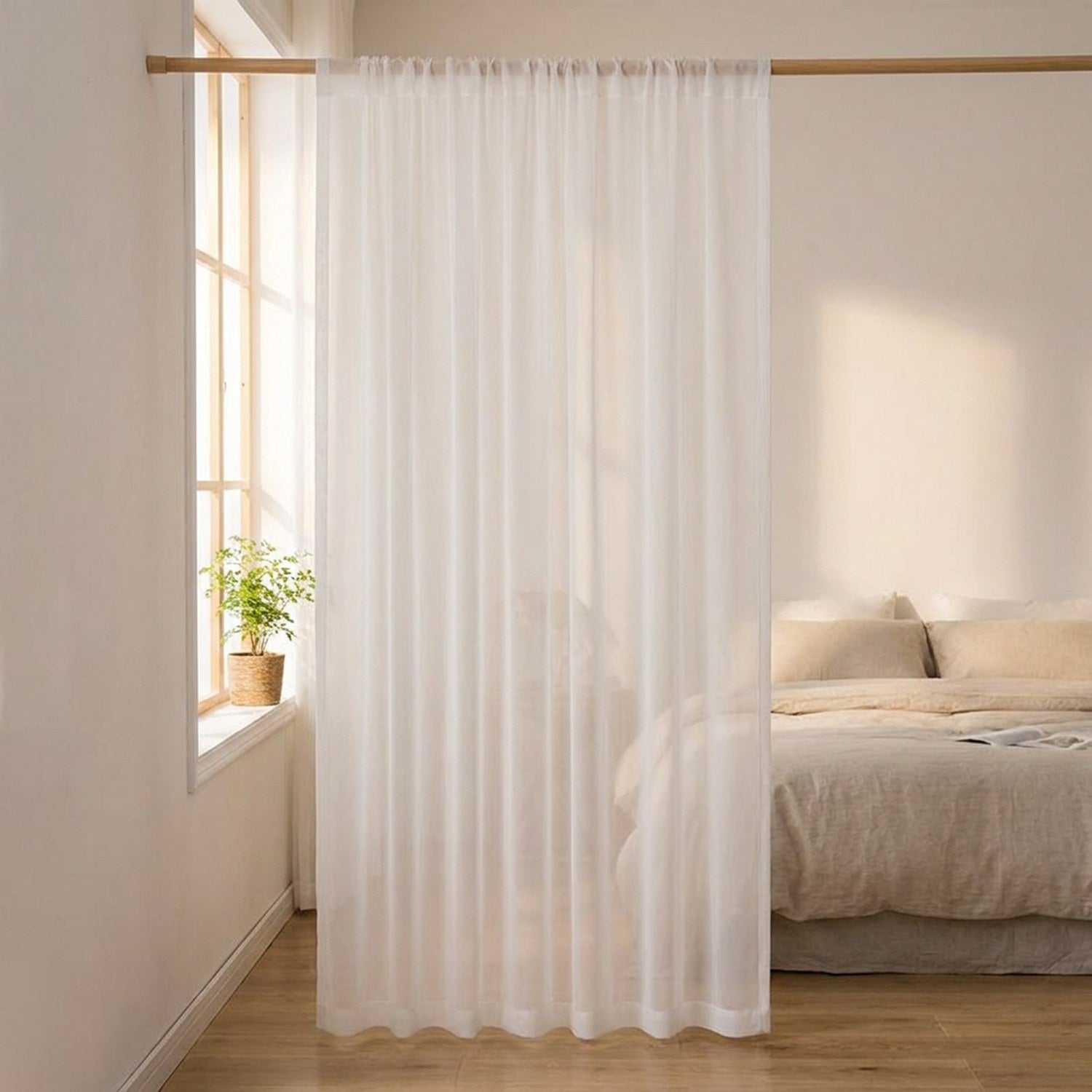 Voilage en tulle blanc suspendu devant une fenêtre de chambre avec plante