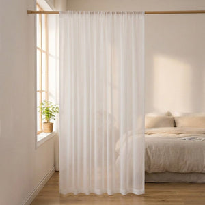 Voilage en tulle blanc suspendu devant une fenêtre de chambre avec plante