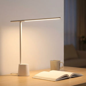 Lampe de bureau blanche éclairant un livre ouvert dans une ambiance chaleureuse