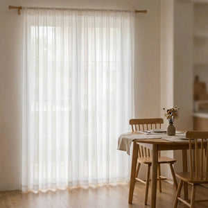 Voilage en tulle blanc près d'une table à manger en bois lumineuse