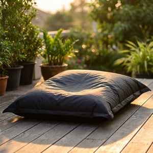 Housse de pouf géant noire imperméable installée sur une terrasse en bois au coucher du soleil