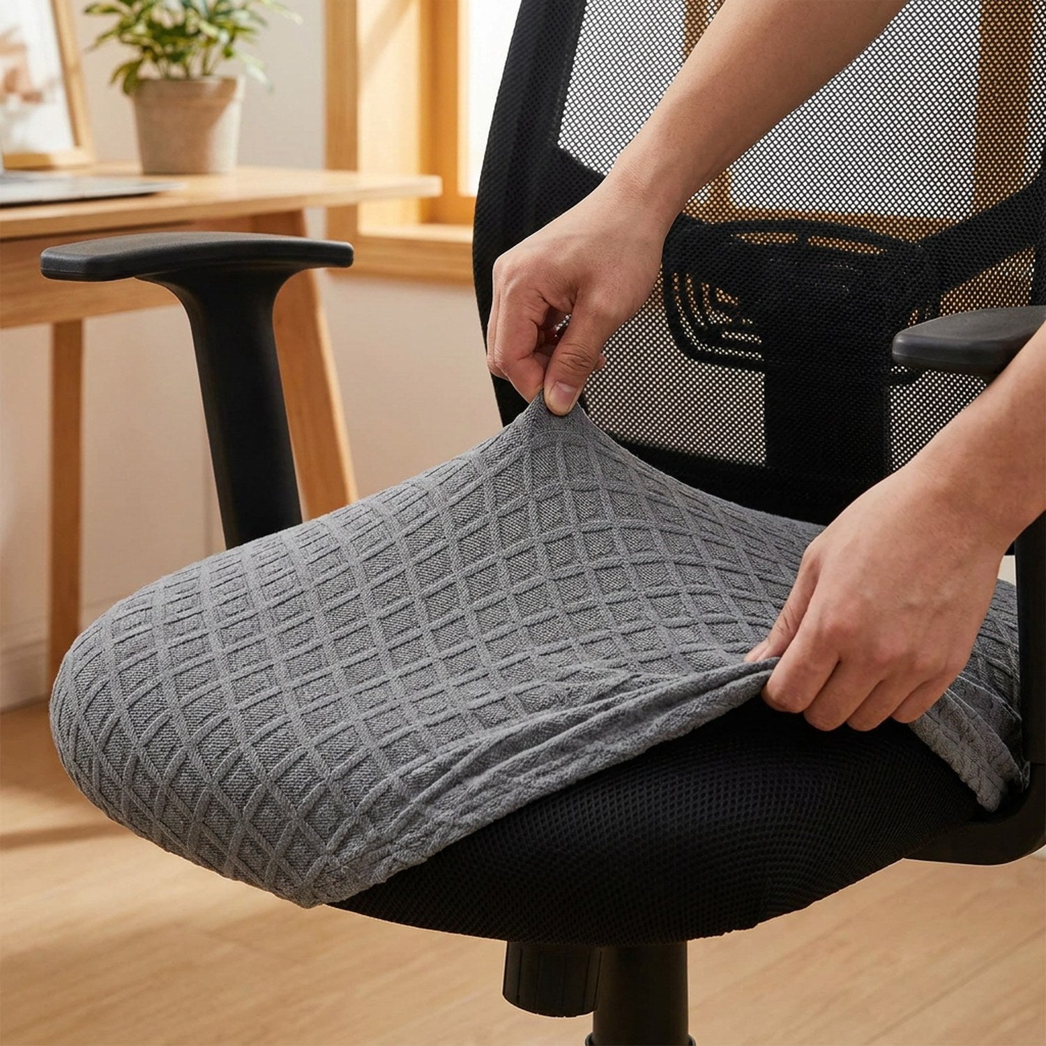 Mains installant la housse extensible sur l'assise d'une chaise