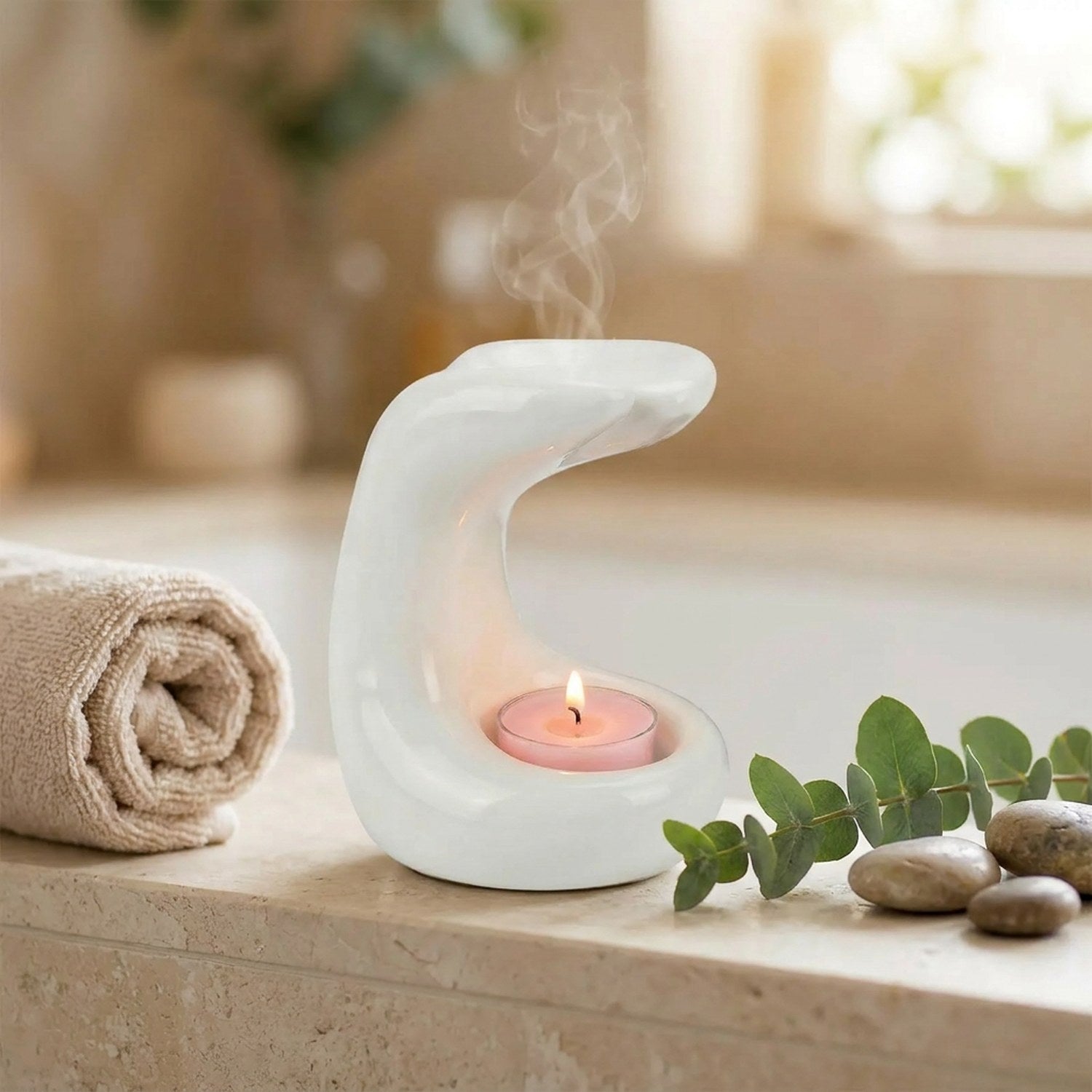 Brûle-parfum en céramique blanche dans une salle de bain zen avec eucalyptus et galets