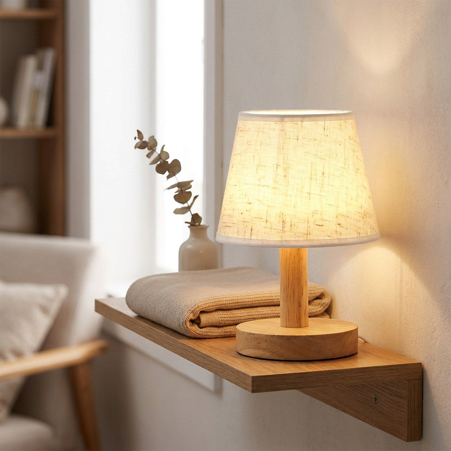 Lampe de chevet rétro allumée sur une étagère murale avec plaid et vase en céramique