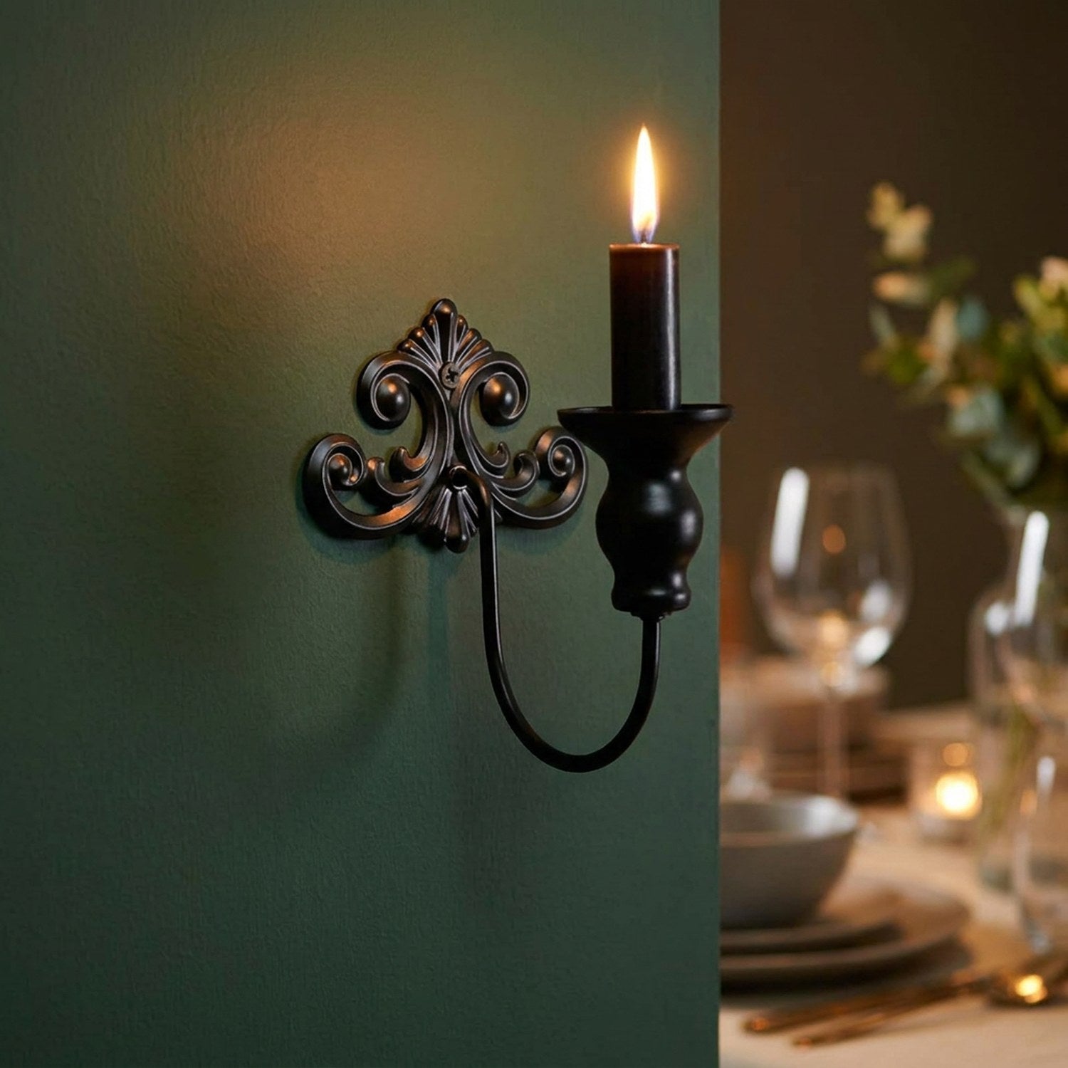 Bougeoir mural noir avec bougie allumée sur un mur vert lors d'un dîner romantique
