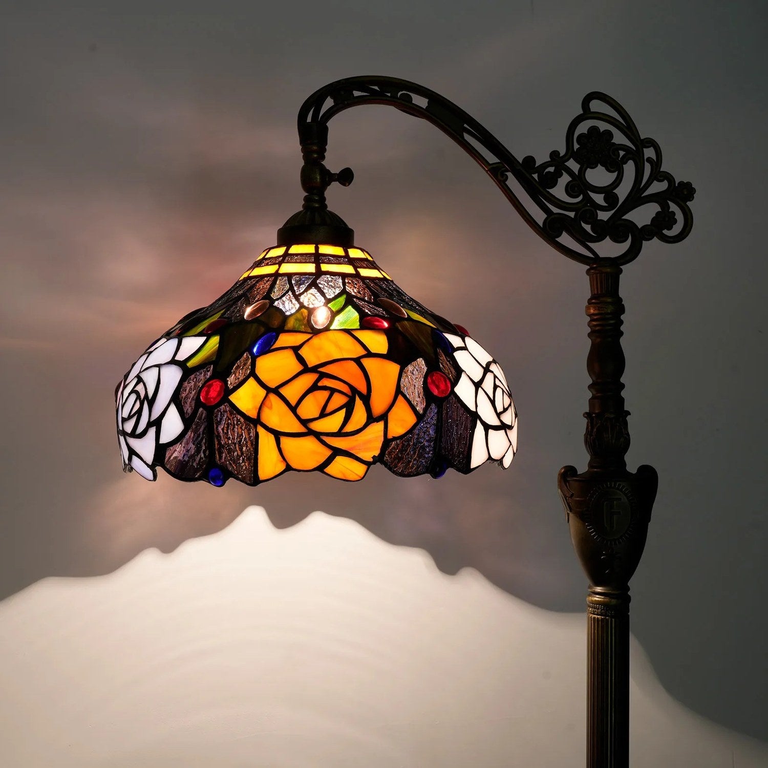 Gros plan sur l'abat-jour en verre teinté du lampadaire style Tiffany aux tons ambrés et roses
